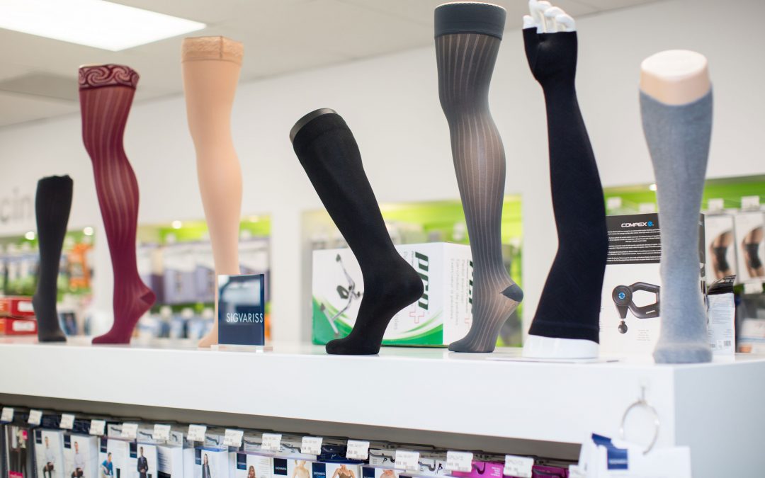 Display of various compression stockings on mannequin legs in a store setting.