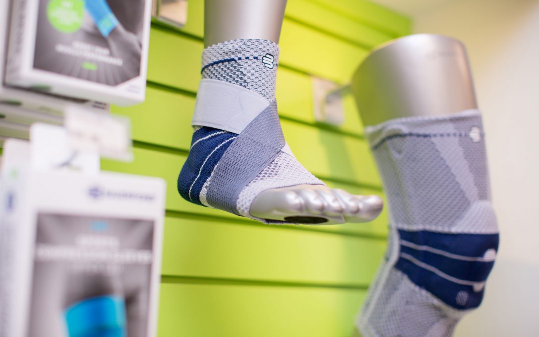Display of orthopedic ankle supports on a mannequin foot against a green wall, with product packaging visible in the background.