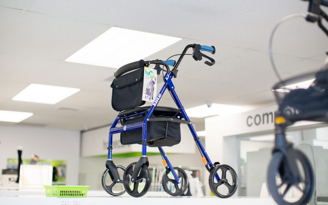 Blue mobility walker with a black storage bag on display in a bright store.